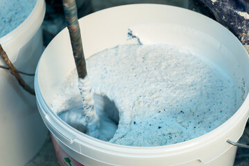 Production of decorative plaster at the factory. Materials for repair and decoration. Closeup of blue decorative plaster mixture in a bowl showcasing texture and contrast.