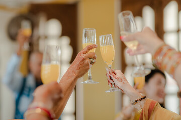Celebratory Toast: Gathering with friends & family with decorated hands holding glasses of sparkling juice for a special occasion.