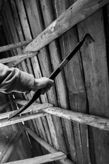 Person gripping a metal prying tool inside a weathered wooden structure