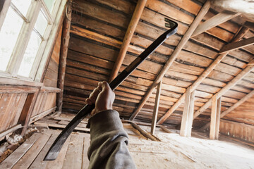 Plakat A person holding a crowbar inside an old wooden attic