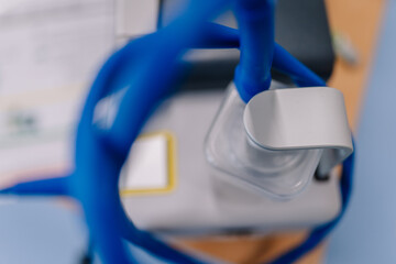 Close-up of blue medical tubing connected to a transparent container with a gray handle, part of a...