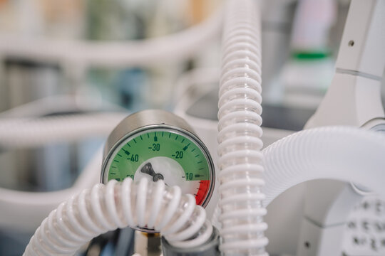 Close-up of a vacuum pressure gauge with coiled medical hoses in a hospital setting, displaying negative pressure values in green and red zones. - Powered by Adobe