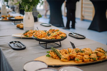 Elegant buffet table with croissant sandwiches and herbs arranged on platters, prepared for an...