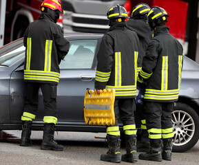 firefighters with yellow stretcher for transporting injured and car during a drill
