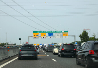 cars in the italian motorway and gate with text that means electronic speed  control