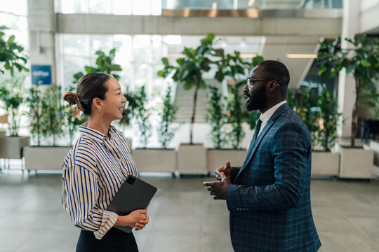 Businesspeople talking in modern office lobby, discussing work strategy