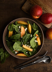 Fresh summer salad with peach, spinach, micro greens, feta cheese on wooden  background. Healthy...