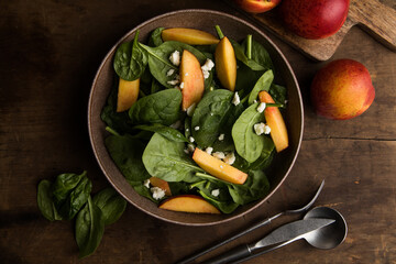 Fresh summer salad with peach, spinach, micro greens, feta cheese on wooden  background. Healthy...