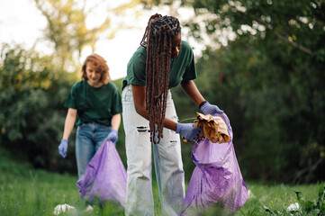 Two young women volunteers picking up trash in park