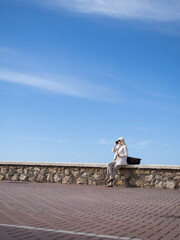 Obraz premium Businesswoman making a phone call on a stone wall under blue sky