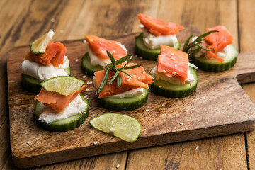 Appetizer canape. Fresh cucumber slices topped with cream cheese and smoked salmon garnished with herbs
