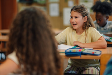 Elementary school girl answering question in classroom during lesson