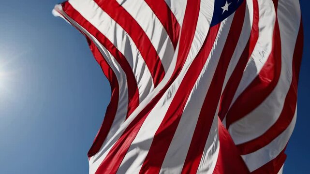 Majestic american flag waves elegantly against blue sky in sunlit sequence