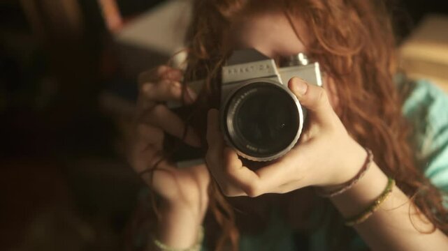 cinematic girl with ginger heir taking pictures, photographer with camera  old antique photo camera, teenager holding vintage retro object. 4k 