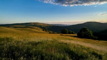 Scenic mountain landscape view with golden meadow, hills, and a sunburst at sunset, against a clear sky with scattered clouds in a serene setting - Powered by Adobe