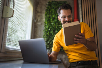 adult man checking box of received package on laptop in the kitchen