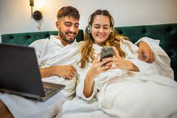 Cozy Couple in Bed Looking at Smartphone Together