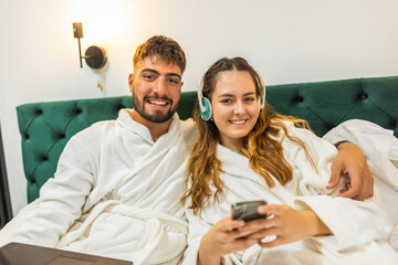 Cozy Couple in Bed Looking at Smartphone Together