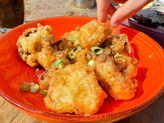 Ladies hand picking up deep fried crispy cauliflower