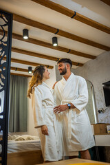 Couple in Bathrobes Looking at Each Other in Hotel Room