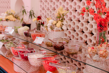 Salad bar with fresh ingredients in bowls, vibrant and colorful. Healthy eating concept. Flower arrangements add elegance. Pink tones create a warm ambiance.