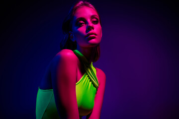 Stylish Young Woman in Neon Lighting Wearing Trendy Green Dress and Posing With Vibrant Colors in...