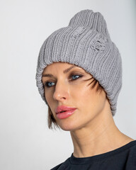 Portrait beautiful woman in grey hat. Pretty girl in warm clothes on grey background. Studio photography. Vertical photo