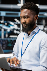 Computer scientist in server room uses laptop to implement and manage data backup solutions....