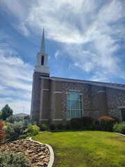 A beautiful church featuring a tall steeple against a blue sky backdrop