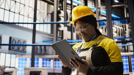 Upbeat professional working in smart factory oversees robot production lines, ensuring quality control. Industry 4.0 plant expert monitoring automated conveyor systems using notebook, camera A