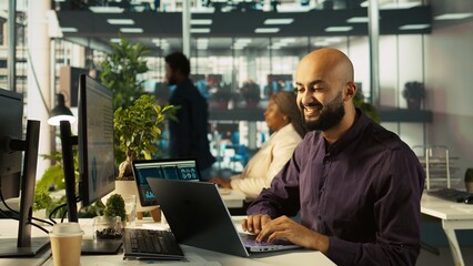 Happy man in office reviewing financial graphs, pleased after seeing good key performance...