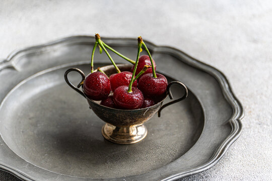 Close-up overhead view of a bowl of freshly washed ripe cherries on a pewter plate - Powered by Adobe