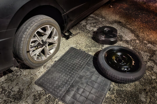 Close-up of a flat tyre being changed on a car by the side of a road