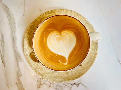 Overhead view of a latte coffee with heart shape latte art on a marble table