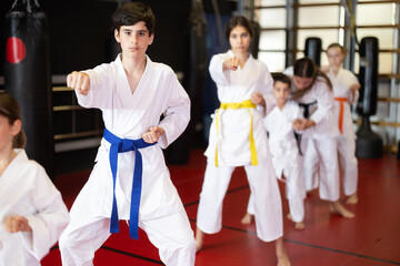 Group of children and teenagers practicing karate technique in gym