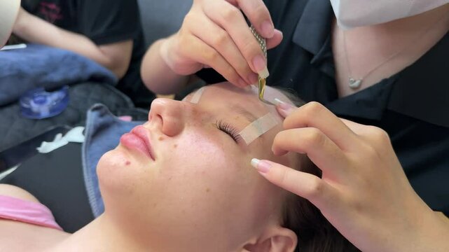 Close up view of eyelash extension procedure using ultraviolet lamp in modern beauty salon. Innovative lash enhancement technology with precise application technique. High quality 4k footage