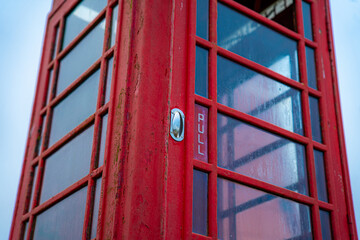 Red telephone booth over a brick wall. Old vintage english telephone booth on a cool background casting shadow.