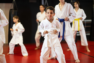 Group of boys and girls in kimonos train karate techniques in studio