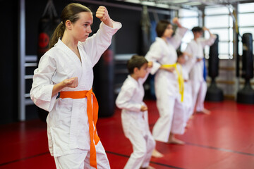 Group of children and teenagers practicing karate technique in gym