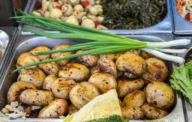 Close-up view of grilled mushrooms displayed with spring onions in a buffet setting, offering a...