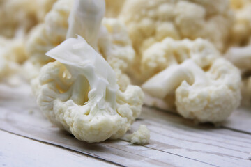 Close-up of the inflorescence of cauliflower. Cauliflower on a wooden surface.
Close-up of fresh cauliflower spread out on a light wooden surface.