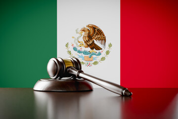 Wooden Gavel Resting on Table In Front of Mexican Flag.