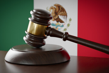 Wooden Gavel Resting on Table In Front of Mexican Flag.