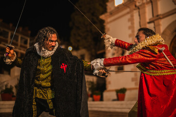 Spanish men in traditional colonial clothing dueling with swords called foils and daggers in a traditional 1600s town setting.