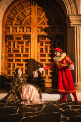 Brunette woman dressed in 1600s period clothing standing in front of an old wooden door.