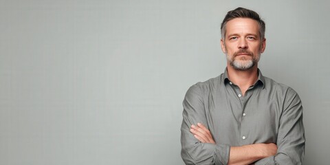 Confident Middle-Aged Man in Gray Shirt Against a Neutral Background