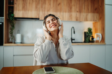 Young caucasian woman enjoying music on wireless headphones at home	