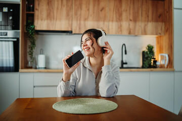 Young caucasian woman enjoying music on wireless headphones at home	