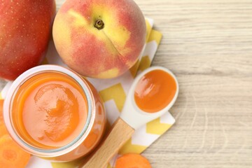 Baby food. Tasty puree in jar, ingredients and spoon on wooden table, flat lay. Space for text
