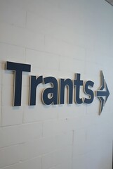 Trants sign with arrow on white wall indicating direction for navigation here